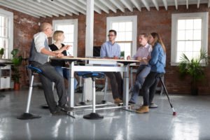 leaning stools around a conference table with people meeting