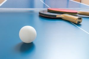 White ball for table tennis or ping pong on wooden table.