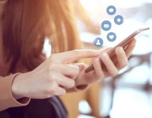 close up of red headed woman on her cell phone with social media symbols