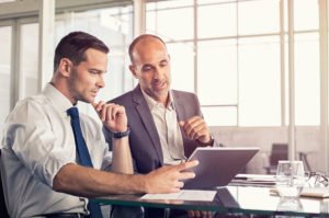 two men discussing something over a tablet computer