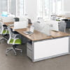 Studio photography of AMQ's Icon Benching. There is two 2-Pack double run workspaces, each with a green cushioned chair placed at the desk. The sun is shining in from the window beyond.