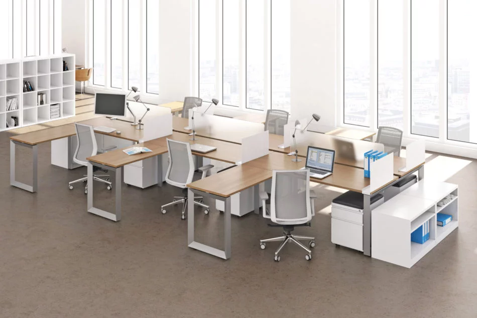 Studio photography of AMQ's Icon Benching. There is two 6-Pack single run workspaces, each with a green cushioned chair placed at the desk. It is using a walnut laminate. Another part of the desk juts out. The sun is shining in from the window beyond.
