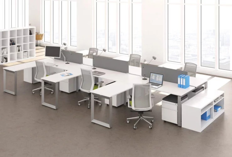 Studio photography of AMQ's Icon Benching. There is two 6-Pack single run workspaces, each with a green cushioned chair placed at the desk. It is using the white laminate. Another part of the desk juts out. The sun is shining in from the window beyond.