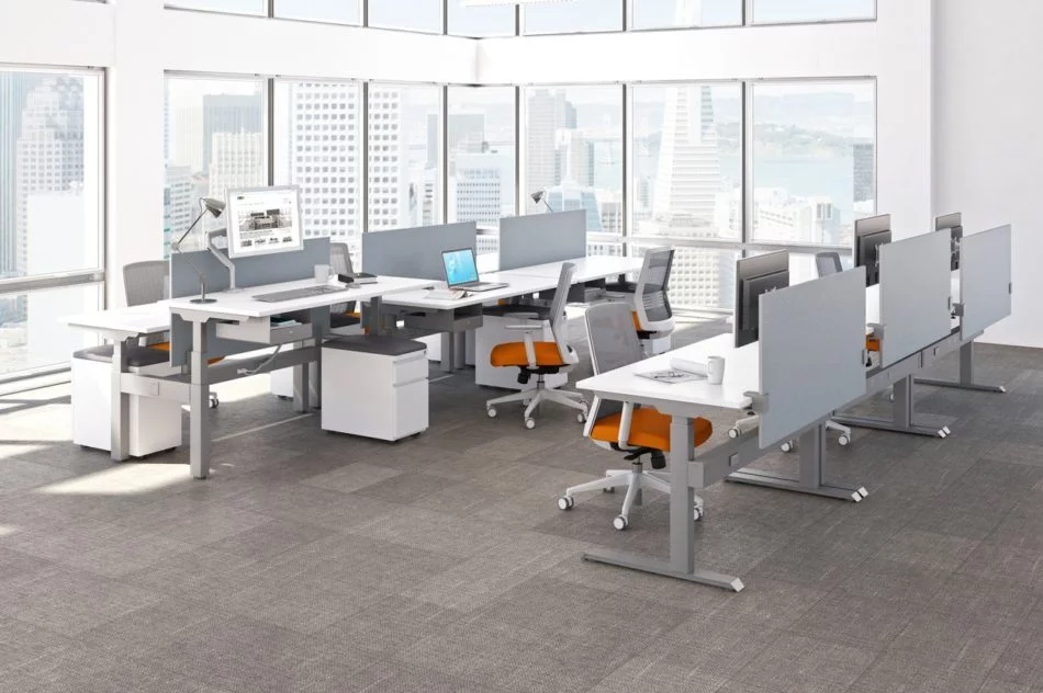 KINEX Studio Shot Showing some double and single run workspaces by the window. Sunlight shines on the white laminate desk top.