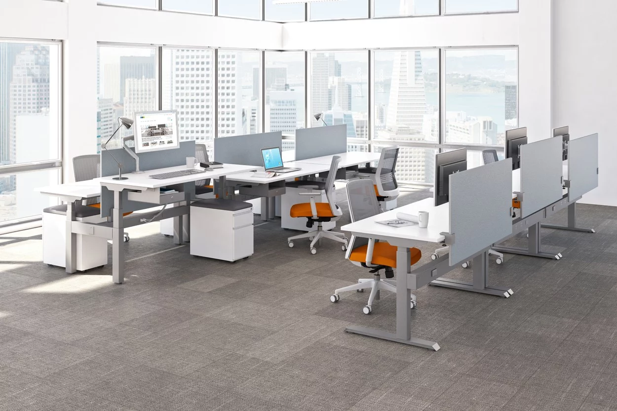 KINEX Studio Shot Showing some double and single run workspaces by the window. Sunlight shines on the white laminate desk top.