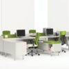 Global's 4-person sidebar benching in a stark white studio set. Each workstation has a flat screen monitor and a green backed rolling chair. The desktop and returns on the side are finished in a white finish.