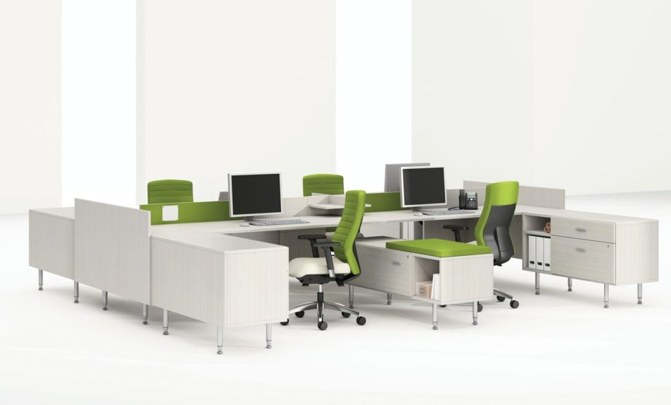 Global's 4-person sidebar benching in a stark white studio set. Each workstation has a flat screen monitor and a green backed rolling chair. The desktop and returns on the side are finished in a white finish.