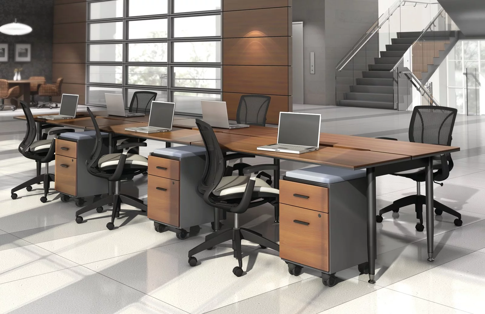 Studio photography of Global's 6-person sidebar benching with a vibrant honey brown finish. Each work station has mobile pedestal drawers and a rolling chair. Beyond, is a flight of stairs and elevator.