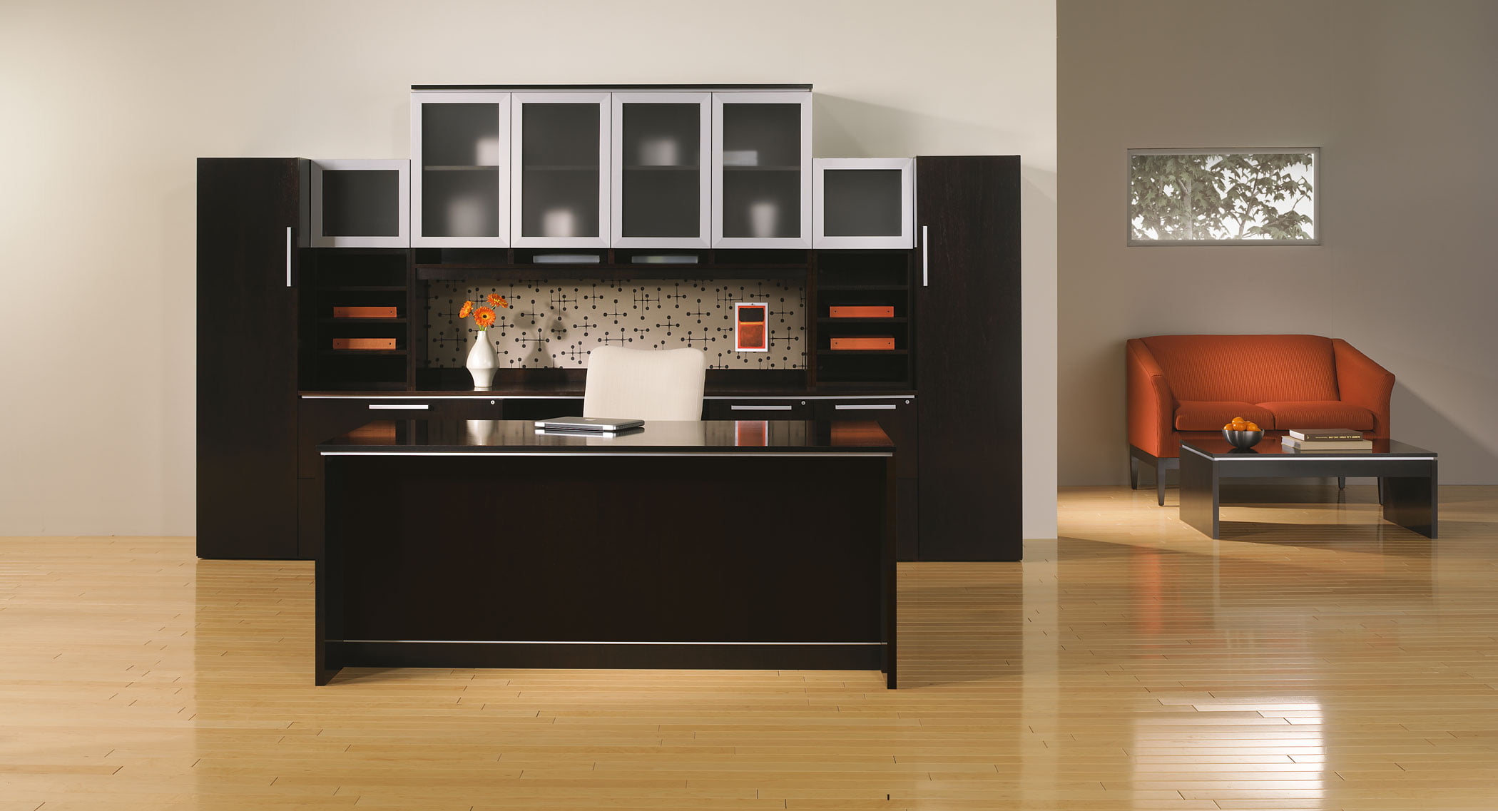 executive desk in dark wood with orange accent sitting area
