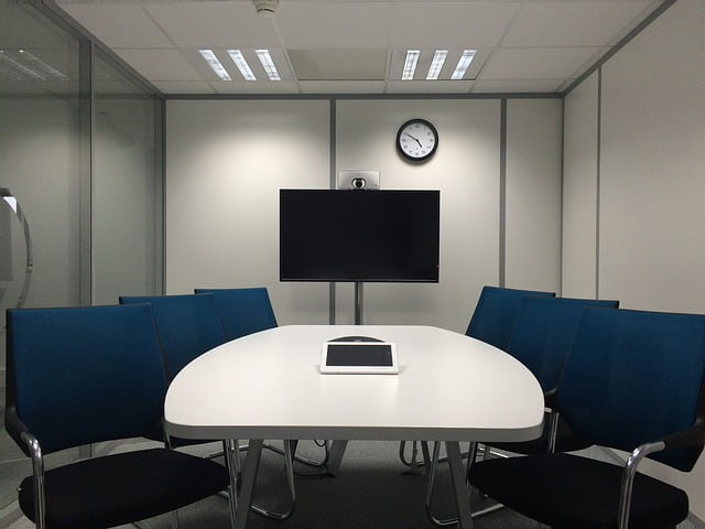 conference room with blue chairs, a white table, and a tv