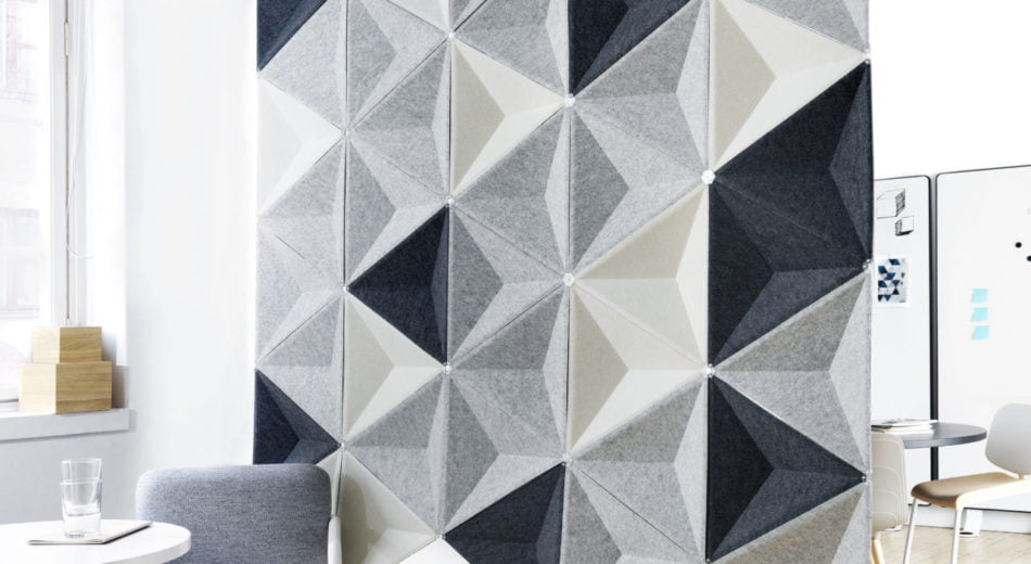 Studio shot of Aircone acoustics formed into a privacy wall. Three different colored pieces are used. There are two sets of chairs and tables broken up by this partition.