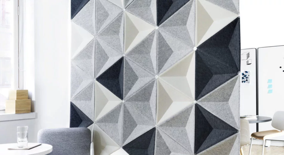 Studio shot of Aircone acoustics formed into a privacy wall. Three different colored pieces are used. There are two sets of chairs and tables broken up by this partition.