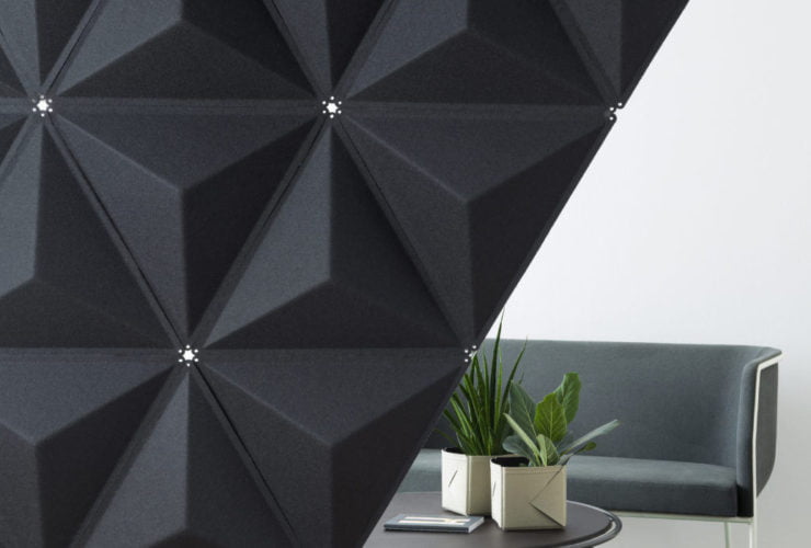 Studio shot of a Aircone wall partition, set up in a white studio. The partition has a diagonal area that shows a couch and coffee table behind.
