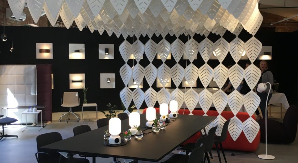 Interior photograph of Airleaf acoustics along the ceiling of a dining area. Additional Airleaf's form a wall just behind the head seat at the table. A red couch is placed just behind it, facing the back wall.