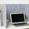Hide privacy screen placed at a white desk. A laptop is open, with a plant to the left side of the Hide screen's wall.