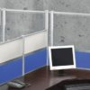 Wide shot of tall Border (model) screens lining the back and sides of two L-shaped desks. Each screen uses clear acrylic, and has a small spacer in between. Two shorter screens divide the desks on the side, with the top panels using frosted acrylic. Each desk has a computer monitor, with a phone at the side.