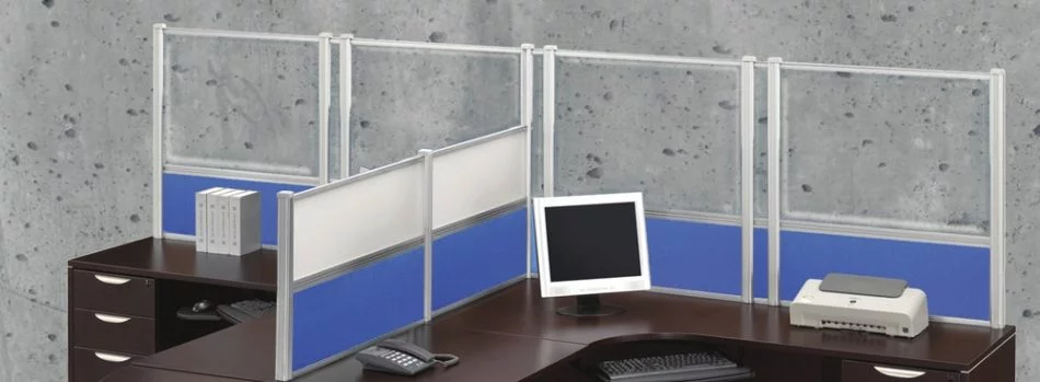 Wide shot of tall Border (model) screens lining the back and sides of two L-shaped desks. Each screen uses clear acrylic, and has a small spacer in between. Two shorter screens divide the desks on the side, with the top panels using frosted acrylic. Each desk has a computer monitor, with a phone at the side.