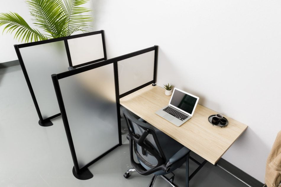 Two workstations are set up along an office wall, with Hitch privacy screens. Each set of paneling over the desk usings a dry erase board panel. One of the laptops is open.