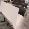 Work table with a Straight(model) space divider, using frosted acrylic. A low backed chair is seated at this table.