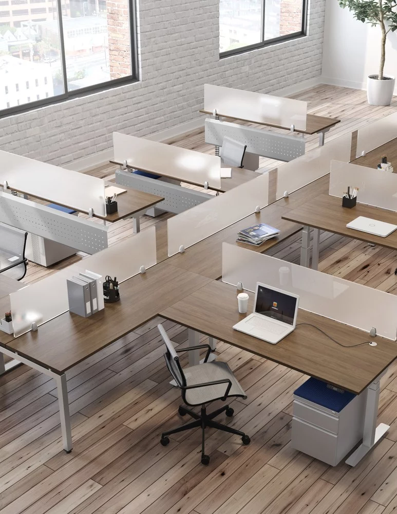 Overhead view of an open office plan, consisting of long benching for 6 or more workstations. Straight (model) screens are placed at the front and the sides of the L-shaped workstations. Windows bring in sunlight.