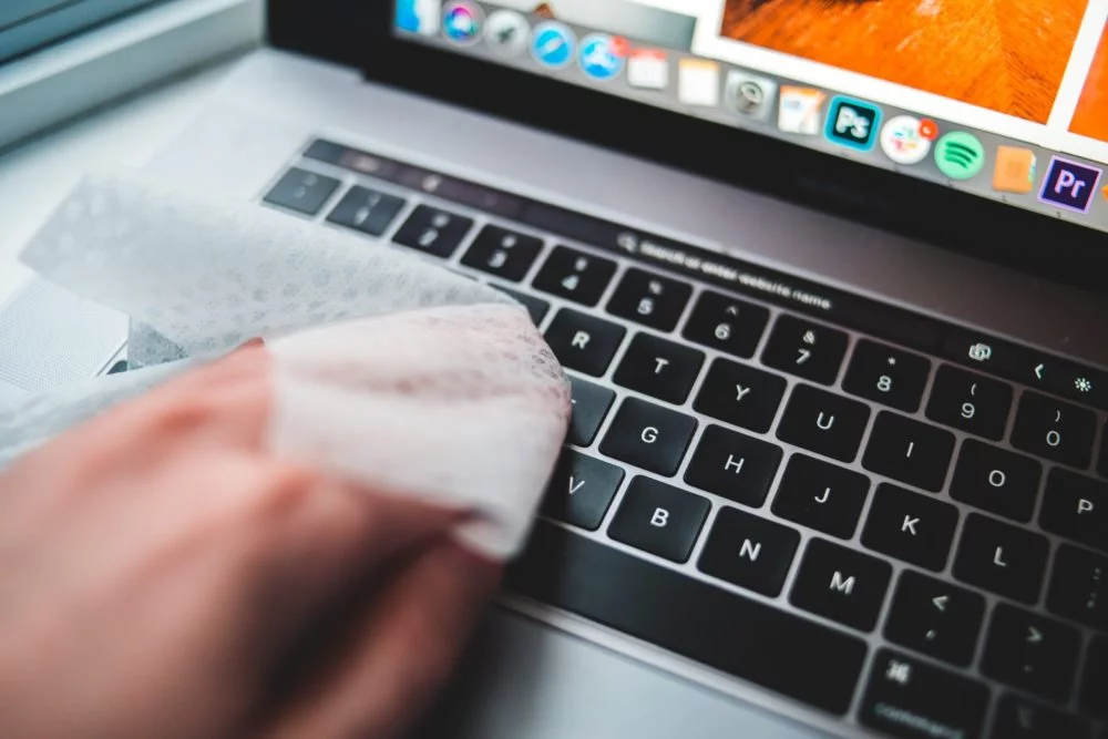 cleaning laptop with disinfecting wipe What You Can Do To Avoid Germs in Your Home Office