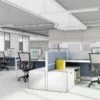 An array of Compile model workstations in an open office plan. Each workstation has a rollaway chair, computer and set of storage to one side.