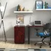 Studio shot of OTG's Home Office Setup, which has a 24" x 48" work table placed in the corner by the window. At the left is a set of pedestal drawers. The third (top) drawer has a lock on it. Both the desk and pedestal drawers are finished in an _____. A simple mesh-back office chair is pulled up to the laptop, with a LED lamp next to it.