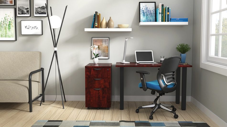 Studio shot of OTG's Home Office Setup, which has a 24" x 48" work table placed in the corner by the window. At the left is a set of pedestal drawers. The third (top) drawer has a lock on it. Both the desk and pedestal drawers are finished in an _____. A simple mesh-back office chair is pulled up to the laptop, with a LED lamp next to it.