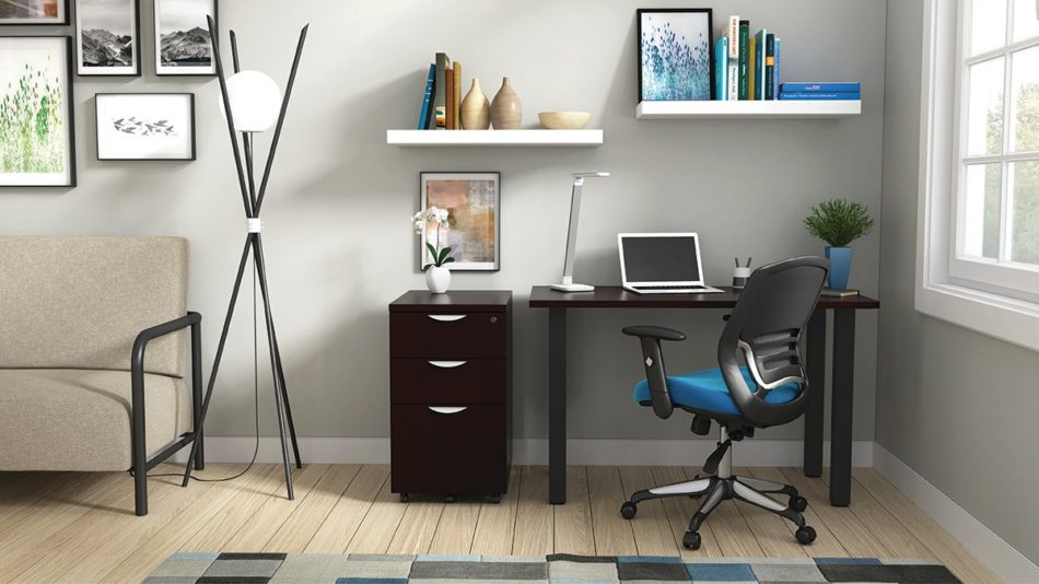 Studio shot of OTG's Home Office Setup, which has a 24" x 48" work table placed in the corner by the window. At the left is a set of pedestal drawers. The third (top) drawer has a lock on it. Both the desk and pedestal drawers are finished in an _____. A simple mesh-back office chair is pulled up to the laptop, with a LED lamp next to it.