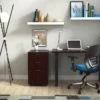 Studio shot of OTG's Home Office Setup, which has a 24" x 48" work table placed in the corner by the window. At the left is a set of pedestal drawers. The third (top) drawer has a lock on it. Both the desk and pedestal drawers are finished in an _____. A simple mesh-back office chair is pulled up to the laptop, with a LED lamp next to it.