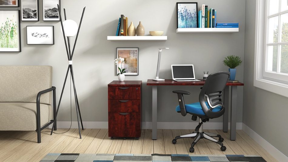 Studio shot of OTG's Home Office Setup, which has a 24" x 48" work table placed in the corner by the window. At the left is a set of pedestal drawers. The third (top) drawer has a lock on it. Both the desk and pedestal drawers are finished in an _____. A simple mesh-back office chair is pulled up to the laptop, with a LED lamp next to it.