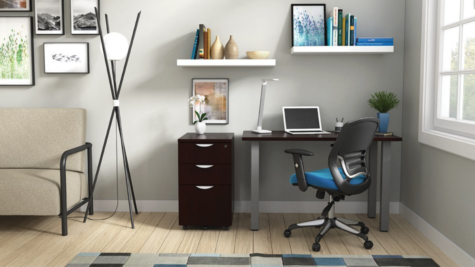Studio shot of OTG's Home Office Setup, which has a 24" x 48" work table placed in the corner by the window. At the left is a set of pedestal drawers. The third (top) drawer has a lock on it. Both the desk and pedestal drawers are finished in an _____. A simple mesh-back office chair is pulled up to the laptop, with a LED lamp next to it.