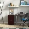 Studio shot of OTG's Home Office Setup, which has a 24" x 48" work table placed in the corner by the window. At the left is a set of pedestal drawers. The third (top) drawer has a lock on it. Both the desk and pedestal drawers are finished in an _____. A simple mesh-back office chair is pulled up to the laptop, with a LED lamp next to it.