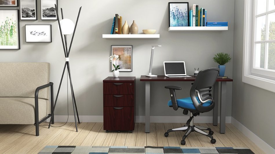 Studio shot of OTG's Home Office Setup, which has a 24" x 48" work table placed in the corner by the window. At the left is a set of pedestal drawers. The third (top) drawer has a lock on it. Both the desk and pedestal drawers are finished in an _____. A simple mesh-back office chair is pulled up to the laptop, with a LED lamp next to it.