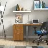 Studio shot of OTG's Home Office Setup, which has a 24" x 48" work table placed in the corner by the window. At the left is a set of pedestal drawers. The third (top) drawer has a lock on it. Both the desk and pedestal drawers are finished in an _____. A simple mesh-back office chair is pulled up to the laptop, with a LED lamp next to it.