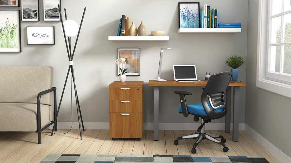 Studio shot of OTG's Home Office Setup, which has a 24" x 48" work table placed in the corner by the window. At the left is a set of pedestal drawers. The third (top) drawer has a lock on it. Both the desk and pedestal drawers are finished in an _____. A simple mesh-back office chair is pulled up to the laptop, with a LED lamp next to it.