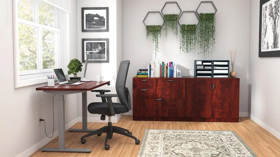 Studio shot of OTG's Home Office Setup, which has a height-adjustable work desk placed at the window. A set of four planters is hung on the wall, above the mixed storage unit. Both surfaces are finished in an American Dark Cherry. A total of four drawers and a double-door cabinet can store different supplies. On top is a set of books, with a giraffe bookend sculpture. A file box to the right holds two columns of slots for important files or as an Inbox.