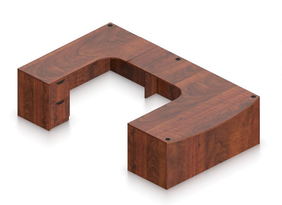 Orthographic view of an Offices to Go set of desking, using Layout B. This set consists of a 71" wide desk, with a curved bow front. A matching width credenza is arranged just across, with a 36" wide flush bridge spanning in between. At the outside of this layout is a set of pedestal drawers, with the second (top) drawer sporting a lock. This desking set is shown in an American Dark Cherry finish.