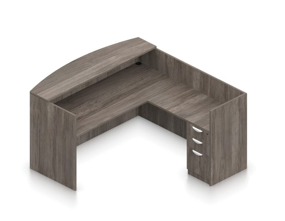 Orthographic view of an Offices-to-Go set of desking, using Layout O. This set consists of a 71 inch receptionist style desk shell, with a 42 inch reversible reception return. At the front, is a matching laminate transaction top. Below the desk surface is a 3-drawer file pedestal, with a lock at the top. This layout is shown in an Artisan Grey finish.