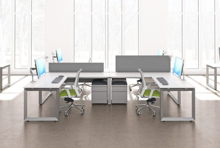 Wide shot of AMQ's Icon Benching. A single workspace, with return is placed next to another in a C formation. At the back of the room, the curtains are drawn on the daylight outside.