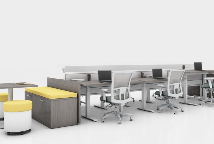 Global's 6-person power beam desks on a white studio set. Each workstation has a laptop open, with glass paneling for privacy. At one end is a cabinet with sunflower yellow cushions, and a square Swap table.