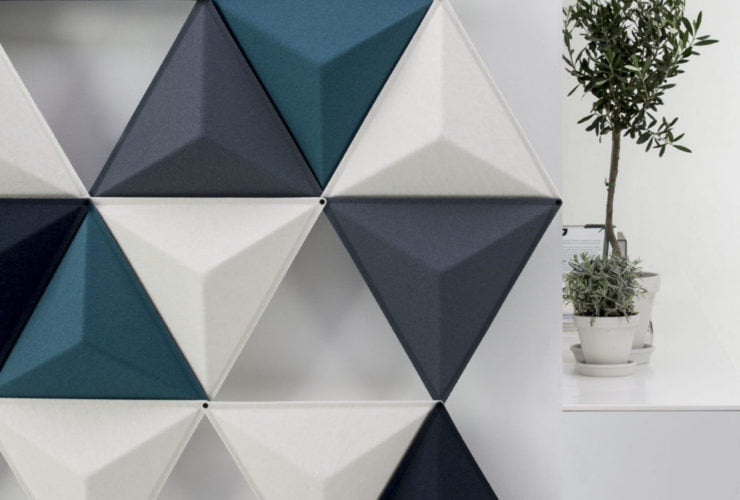 Studio shot of the Aircone acoustic panels in a pale room. This partition uses three different colors of Aircones. The Diagonal sides reveal a white platform with tall potted plants set on top.