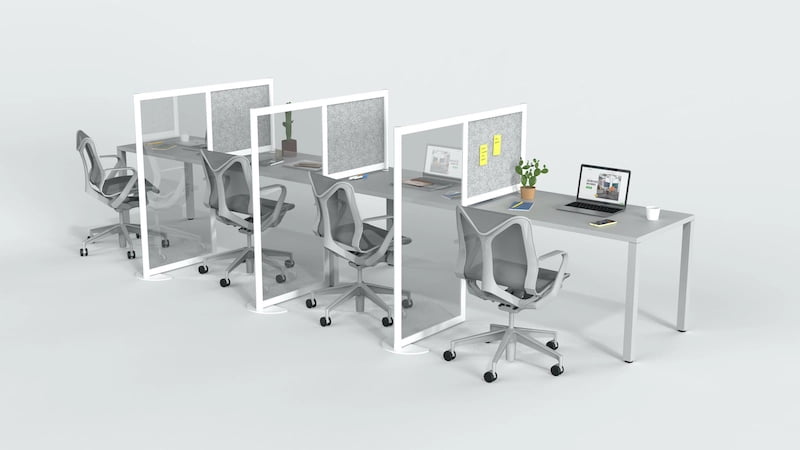 A medium desk set for four office workers. A Hitch partition seperates each station. The work desk nearest to us sports a potted plant. Stick-it notes are place on panel of the first Hitch screen.