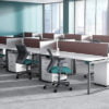 Open office space, featuring two rows of desks. A Run II mid-back office chair is placed at each work area, a teal green seat cushion and black mesh back.